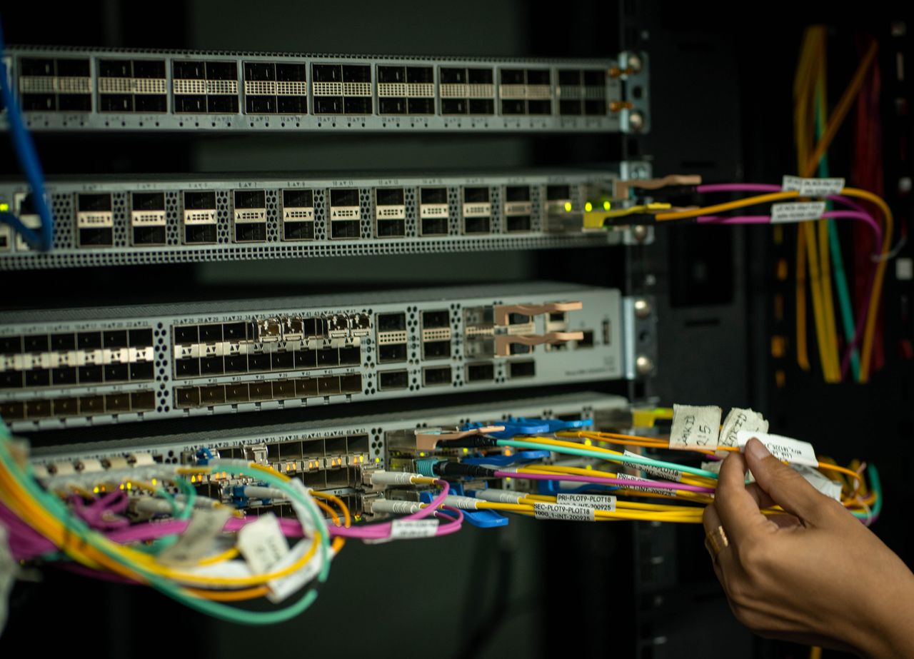 Mastering the First Impression: Your intriguing post title goes here A hand managing fiber optic cables in a server room, showcasing modern connectivity.