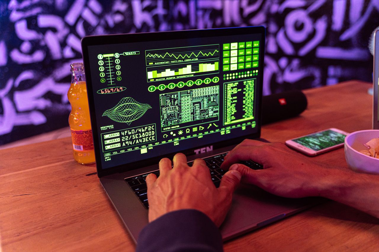 Crafting Captivating Headlines: Your awesome post title goes here A person typing on a laptop displaying green code with an orange bottle and smartphone nearby.